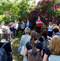 Eine Menschenmenge, die im Wald steht und einem Sprecher zuhört.